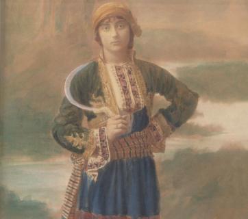 Επιχρωματισμένη φωτογραφία του Emile Lester στην οποία απεικονίζεται Αθηναία δέσποινα της εποχής του Μεσοπολέμου ντυμένη με ενδυμασία από την Μάνη. Συλλογή Λυκείου των Ελληνίδων