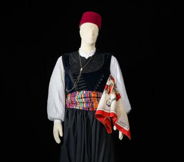 Νεότερη ανδρική γιορτινή φορεσιά από τα Παλάτια με μαντήλι μαρκομπότσαρη που ανήκε στον Παλατιανό Γεώργιο Ιωαν. Χατζηιωάννου (Γιωργιός). Το μαντήλι φέρει κεντημένο το όνομα του κατόχου και την χρονολογία 1897. Ευγενική παραχώρηση της Ασημένιας Δράκου–Χατζηιωάννου. Το γιαλελί (γιλέκο) και το πουκάμισο ανήκουν στον Λάζαρο Δράκο, ενώ η βράκα και το φέσι στον Ηλία Καφτάνη. Φωτογραφία: Studio Kominis